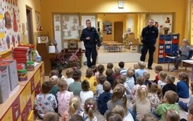 Dzieci słuchają pogadanki policjant&oacute;w na temat bezpieczeństwa
