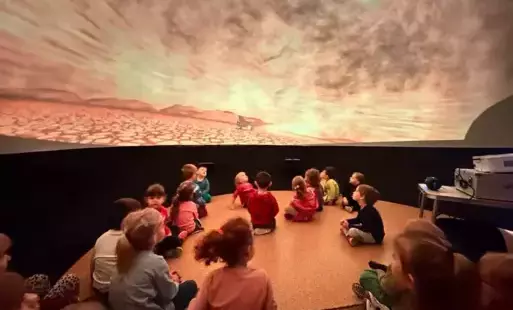 dzieci oglądają film w mobilnym planetarium